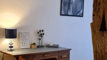 A room with a wooden desk, a chair, a framed picture on the wall, and a large tree trunk.