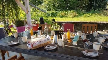 Aamiaiselle katettu pöytä, jossa on erilaisia ruokia, juomia ja ruokailuvälineitä.