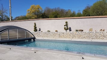 Una piscina al aire libre de temporada, sombrillas