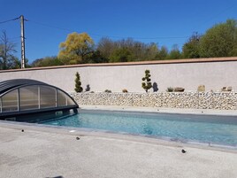 Piscina com parede de pedra e estrutura metálica.