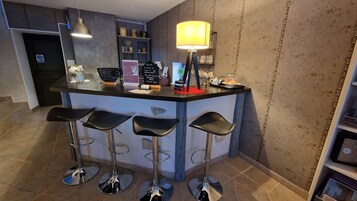 Uma área de bar com quatro banquetas, um balcão, uma luminária e um menu em lousa.