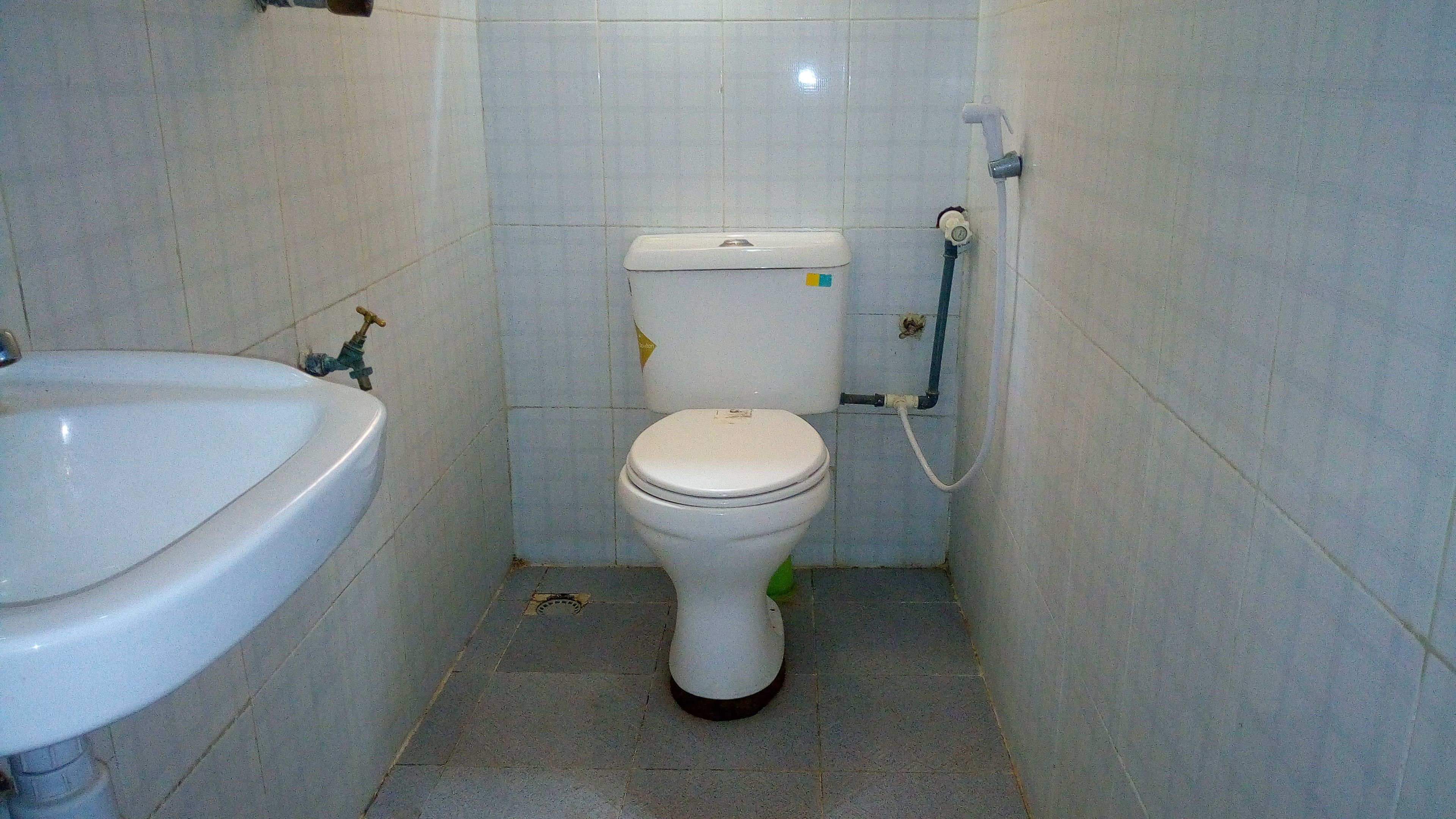 A small bathroom with a white sink, toilet, and a visible pipe on the wall.