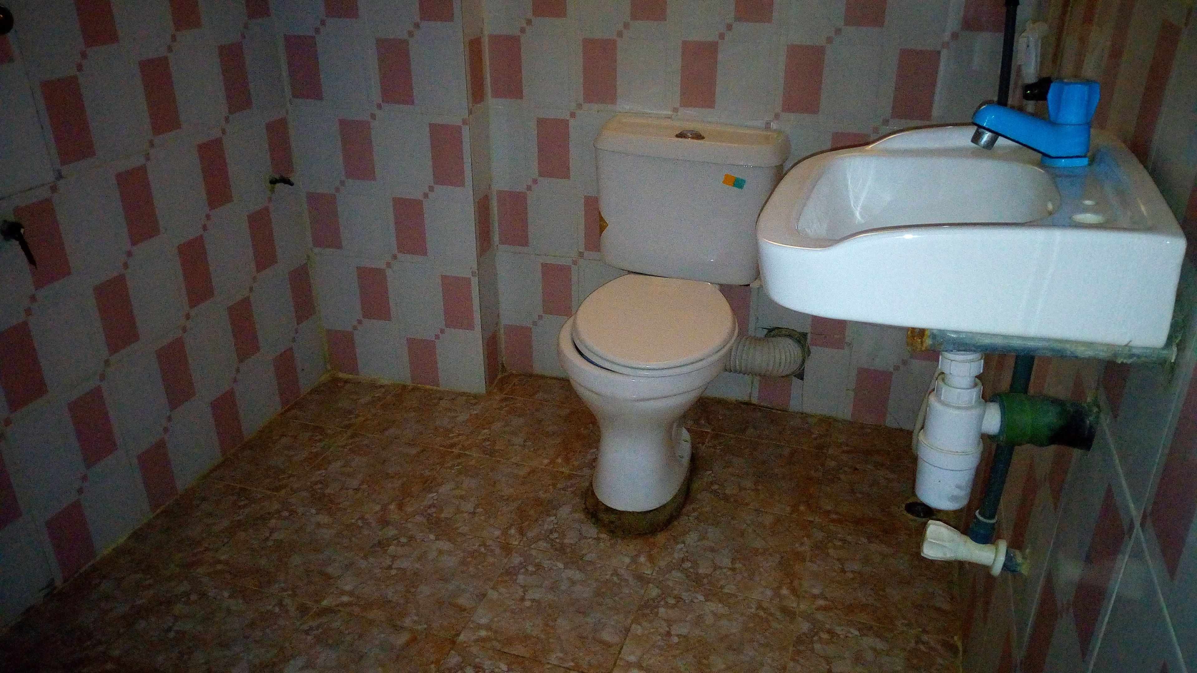 A small bathroom with a toilet, sink, and tiled walls.