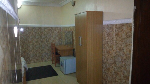 Una habitación pequeña con un armario de madera, una mesita y un refrigerador.