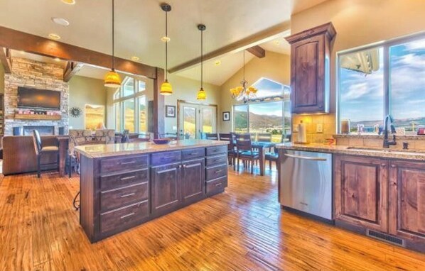 A spacious kitchen with a large island, wooden cabinets, and a stone fireplace. - Unobstructed Lake View 10 min to Snowbasin, Sleeps 12 (Huntsville)