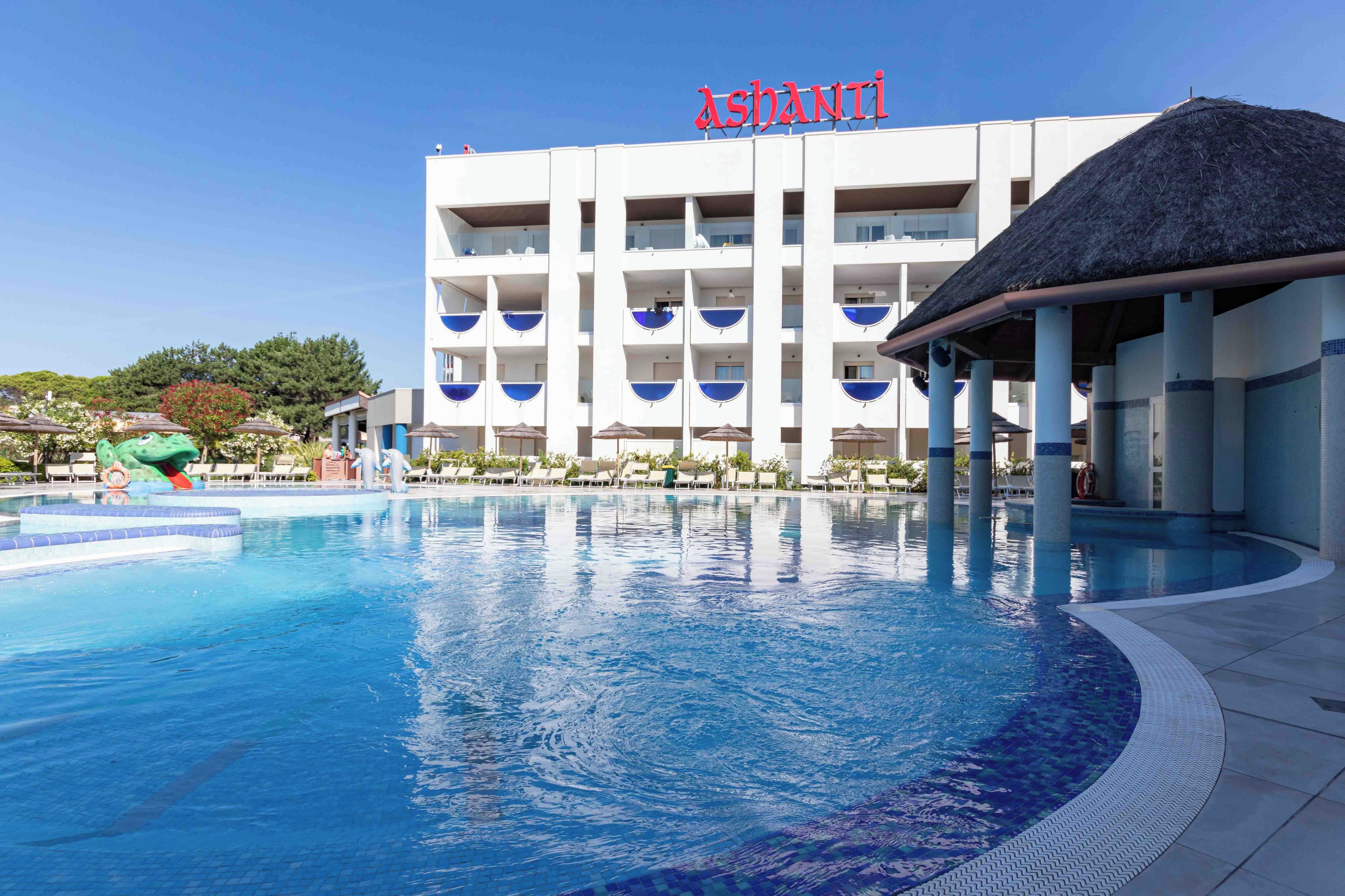 Ein Hotel mit Schwimmbad, mehreren Balkonen und einem Reetdach.