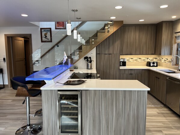 Una cocina moderna con una isla central, estufa integrada y un lavamanos de acero inoxidable.