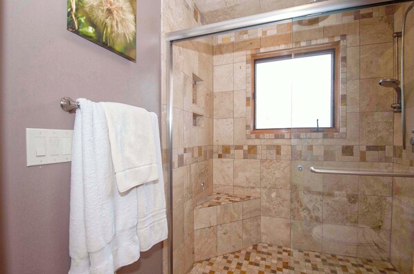 Un área de ducha con puerta de vidrio, ventana y suelo de baldosas.
