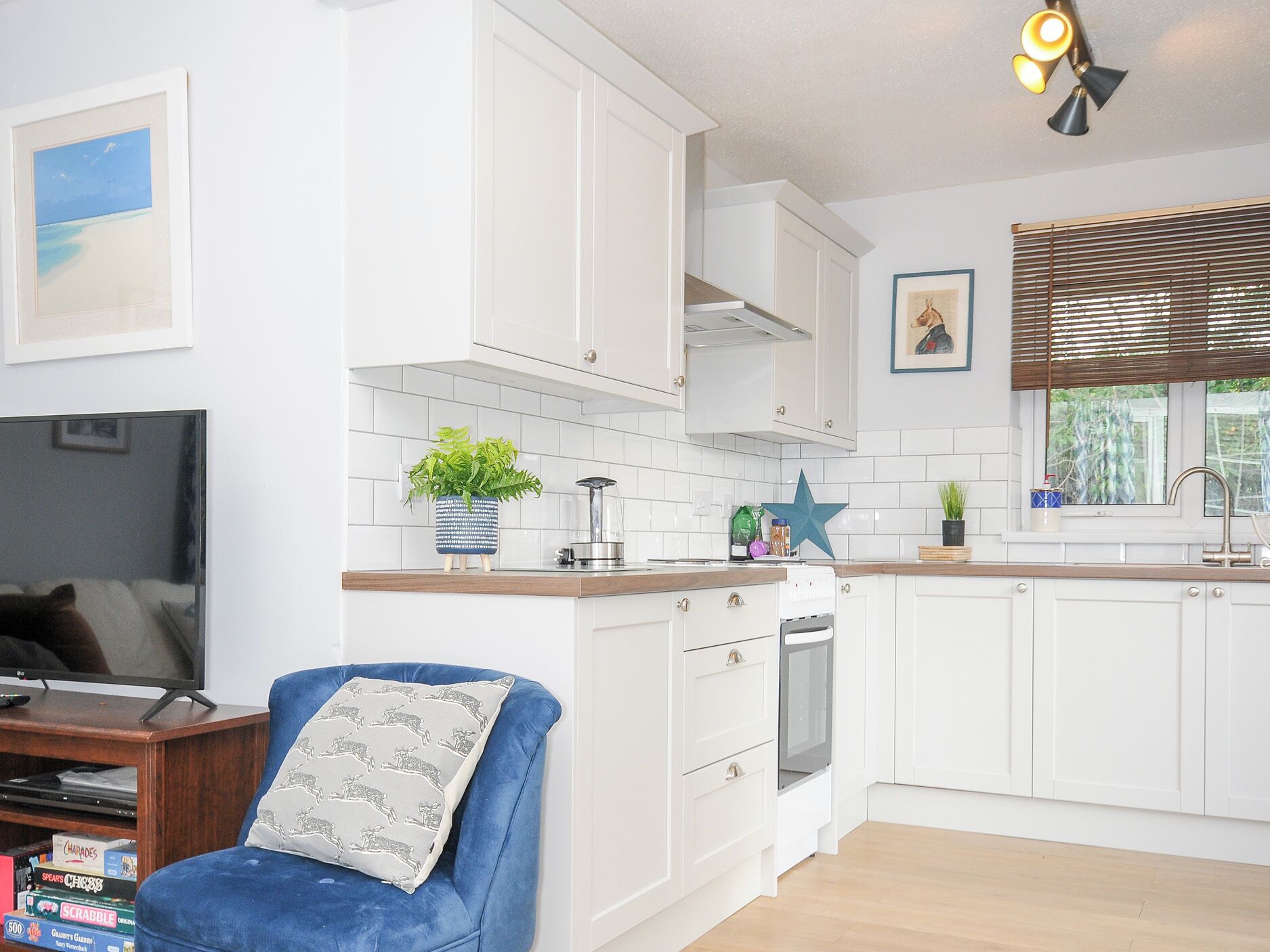 A modern kitchen with white cabinets, a built-in oven, and a window with blinds.