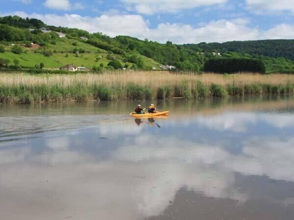 A calm lake with a person in a yellow kayak. - Tuckermarsh Quay River Cottage 2 (Yelverton)