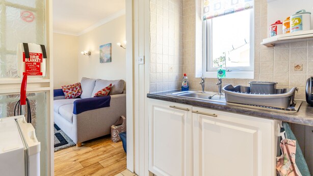 A compact kitchen with a sink, countertop, and a window with a view. - 19 Cormorant Drive (St Austell)