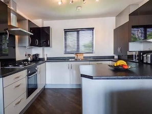 Enjoy cooking in this well-equipped kitchen with a central island, stove, and kettle.