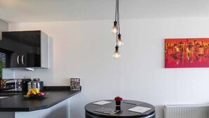 A modern kitchen with a black countertop, a round black table, and a red vase.