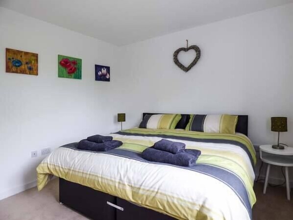 A bedroom with a bed, a small table, and three wall-mounted artworks. - Tehidy (St Austell)