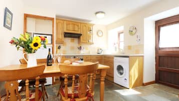 Una cocina con armarios de madera, lavadora y una mesa de comedor con sillas.