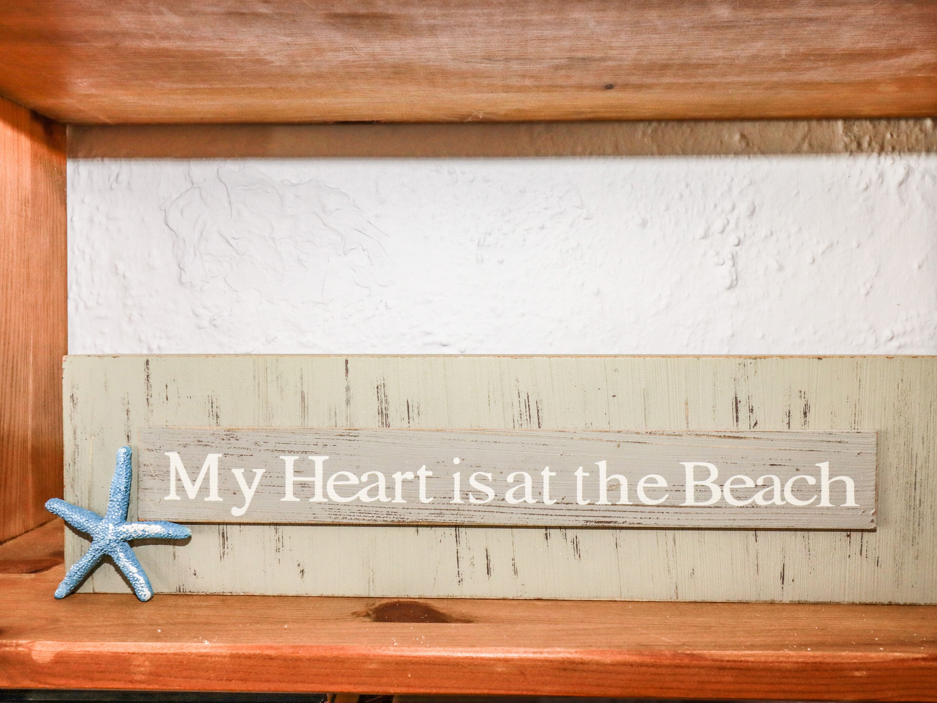 A wooden shelf with a sign that reads "My Heart is at the Beach" and a blue starfish decoration.
