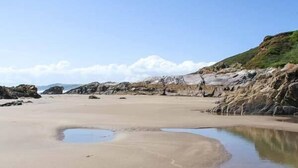 A beach with a sandy shore and a small water body.