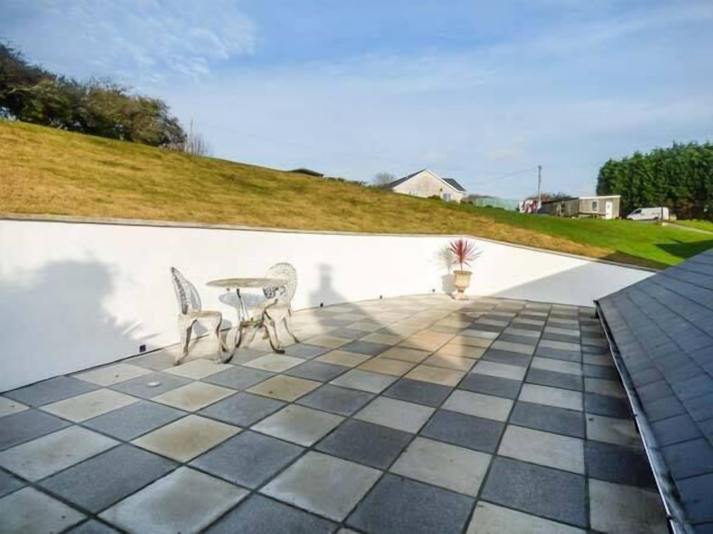 A patio with a checkered floor, a small table, and chairs.