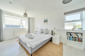 Une chambre à coucher avec un lit, des tables de chevet, une bibliothèque et de grandes fenêtres.