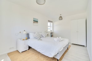 A bedroom with a bed, bedside table, lamp, and a window with a view. - Brook House (Penzance)