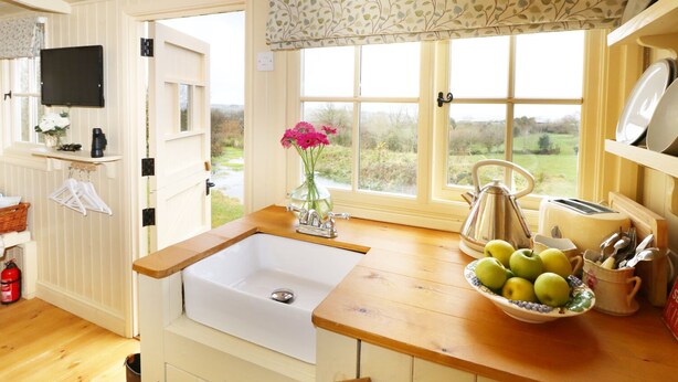 Una cocina con un lavamanos blanco, encimera de madera y ventana con vistas al exterior.