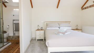 Un dormitorio con cama, mesitas de noche, baño con inodoro y ducha.