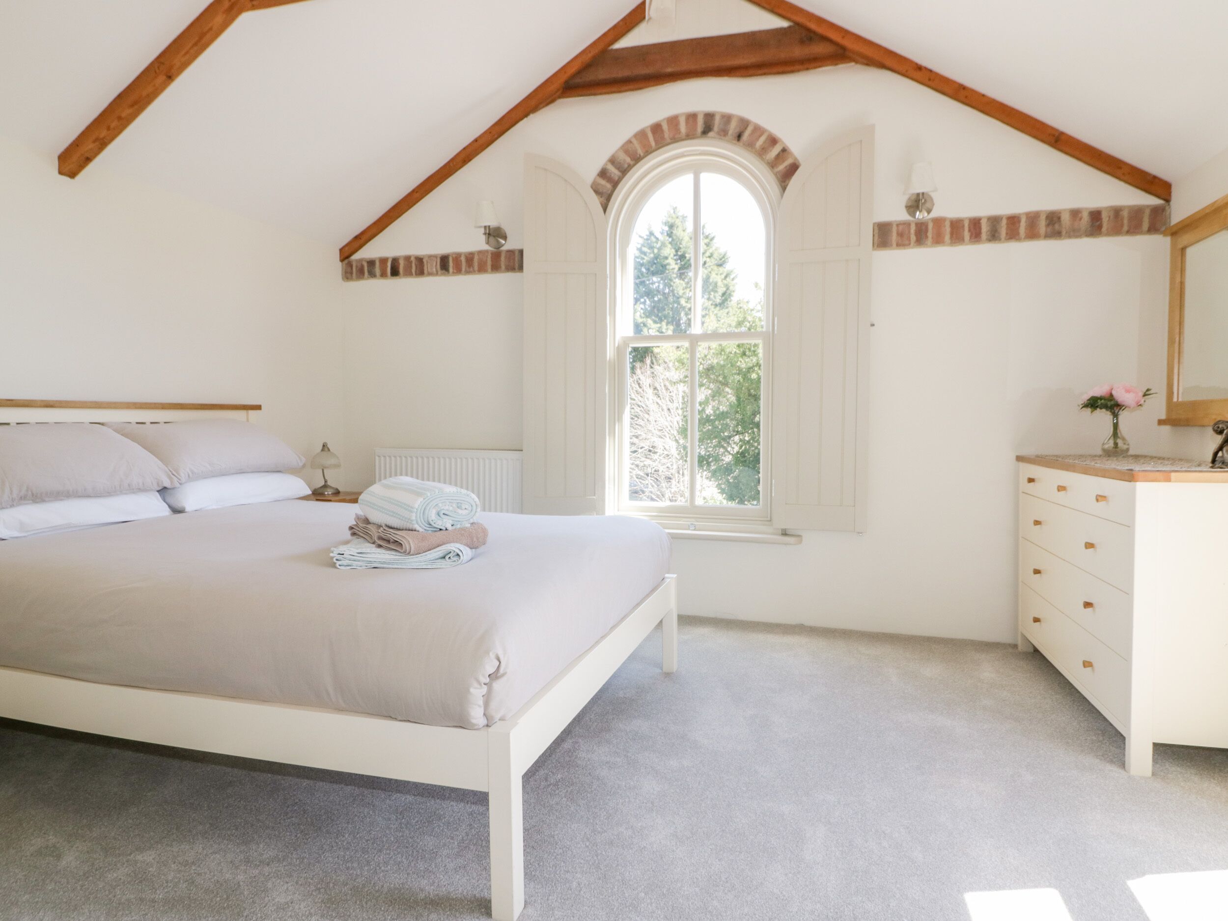 Une chambre à coucher avec un lit, une commode, une fenêtre et un radiateur.