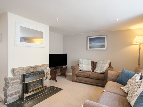A living room with a fireplace, a television, a couch, and a lamp. - 5 Bodmin Hill (Lostwithiel)