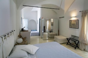 Un dormitorio moderno con una cama grande, una mesita de noche, un espejo y vistas a otra habitación.
