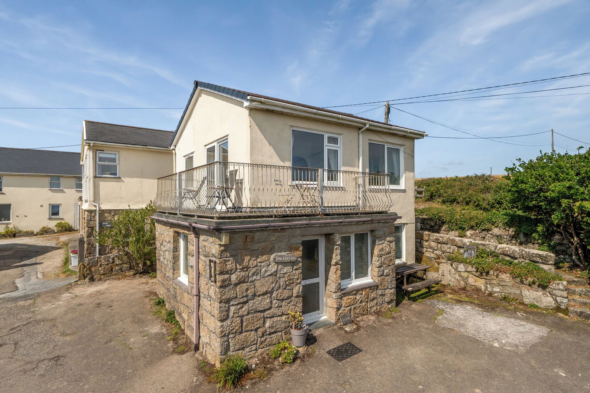 A two-story building with a stone base and a balcony with metal railings.