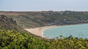 Un paysage côtier avec une plage, des maisons et une colline couverte de végétation.