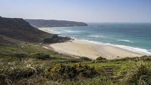 A coastal landscape with a beach, cliffs, and a clear sky. - The Coach House (Penzance)