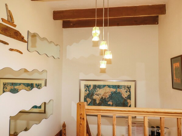 Una habitación con vigas de madera, barandilla de madera y un mapa en la pared.