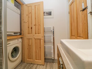 Una lavanderia con lavatrice, stendibiancheria e una porta di legno.