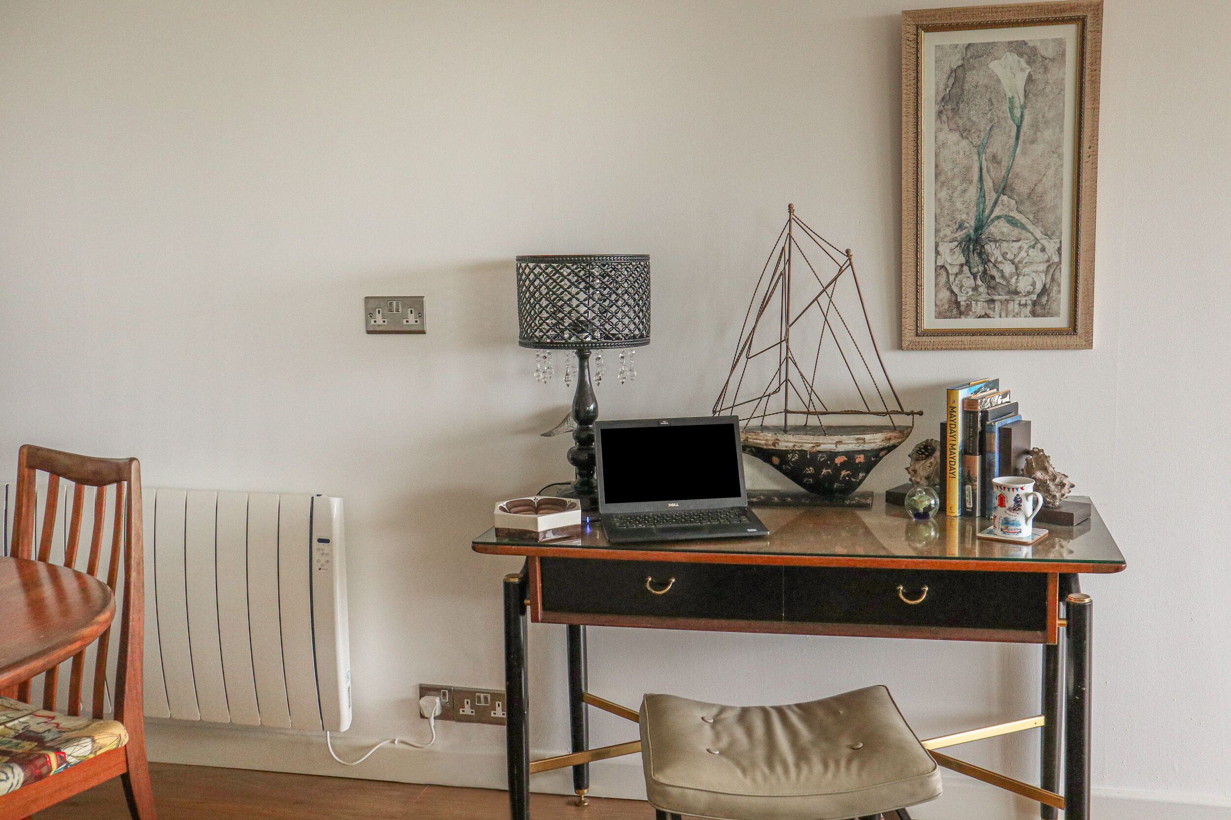 Ein Holztisch mit einem Laptop, einer Lampe und dekorativen Gegenständen. Ein Stuhl steht davor.