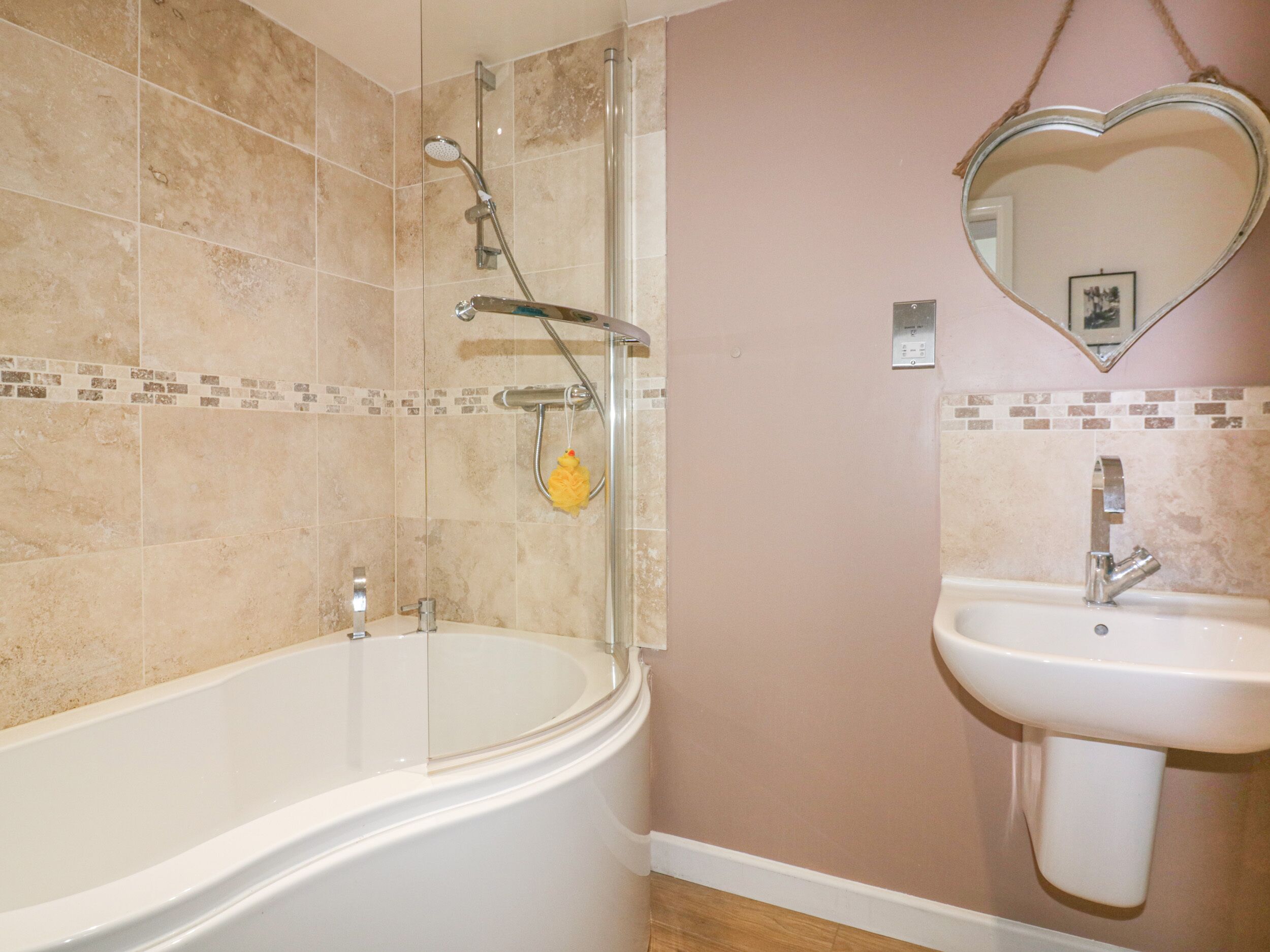 Ein Badezimmer mit einer freistehenden Badewanne, einer Dusche und einem Waschbecken mit herzförmigem Spiegel darüber.