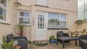 A patio with outdoor furniture, potted plants, and a white door. - Spindrift (Newquay)