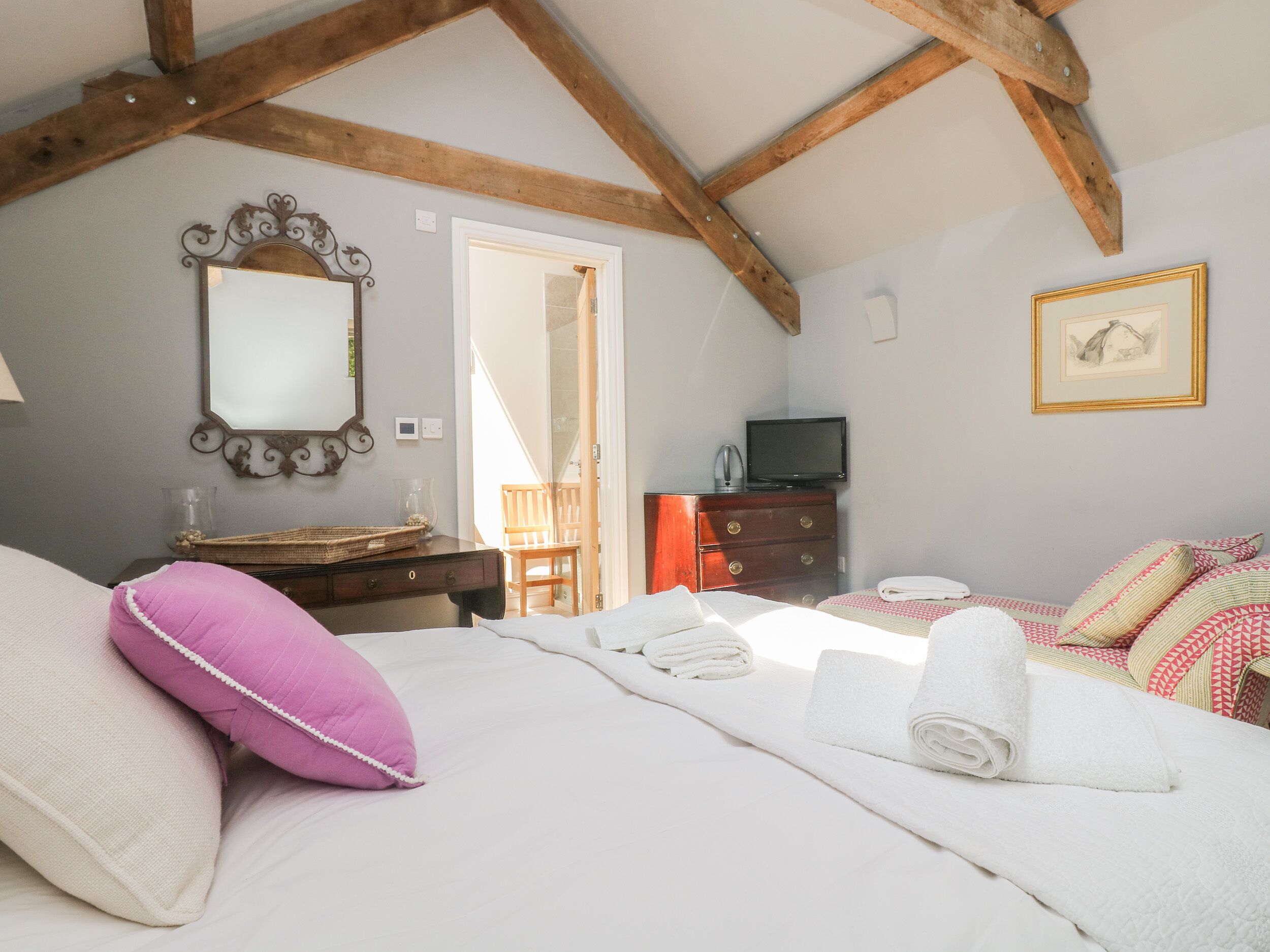 A bedroom with a bed, a dresser, a television, and a mirror.