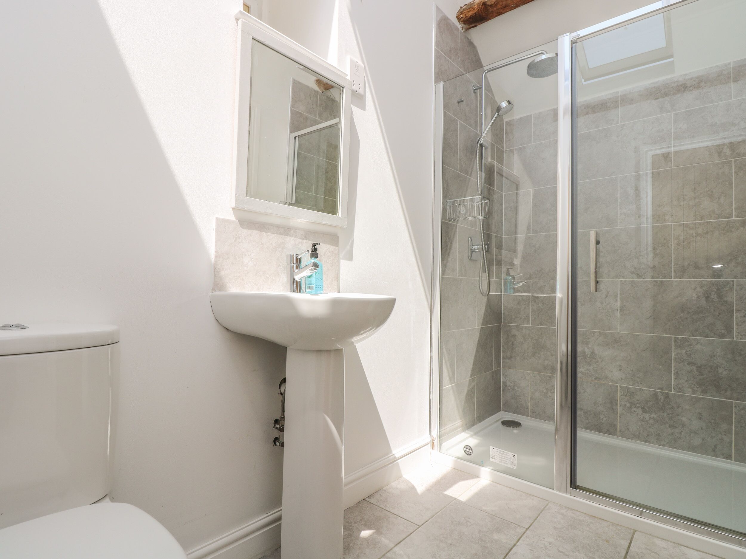 A bathroom with a toilet, sink, and glass shower enclosure.