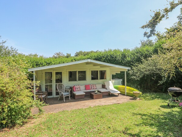A small, single-story house with a covered porch and a brick patio. - Little Chycoose (Truro)