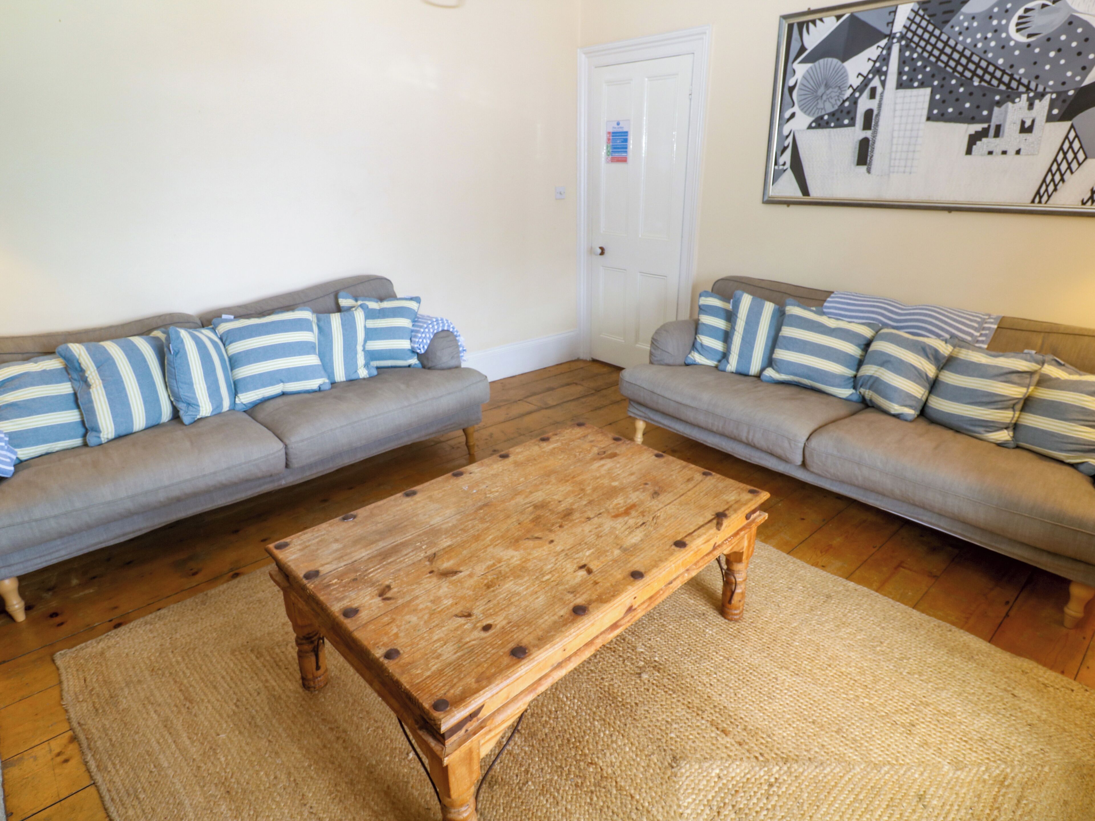 A living room with two grey sofas, a wooden coffee table, and a framed picture on the wall.