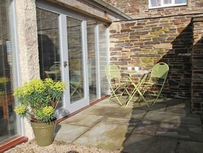 Relax on the patio with two comfortable chairs and a small table, surrounded by lush greenery.