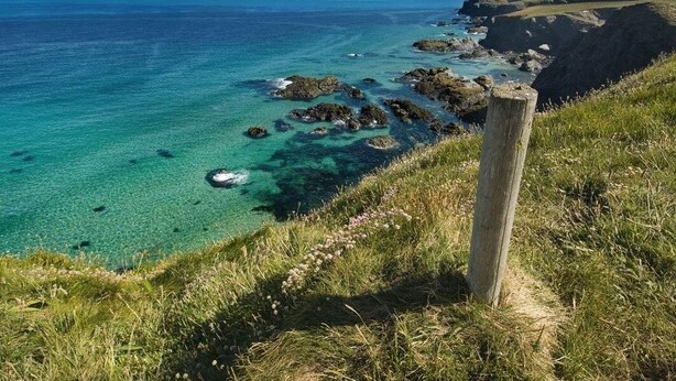 A coastal landscape with clear turquoise waters, rocky outcrops, and grassy terrain. - The Old Dairy (Wadebridge)