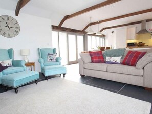 Relax in this stylish living room with a high ceiling, comfortable sofa, and cozy armchair.