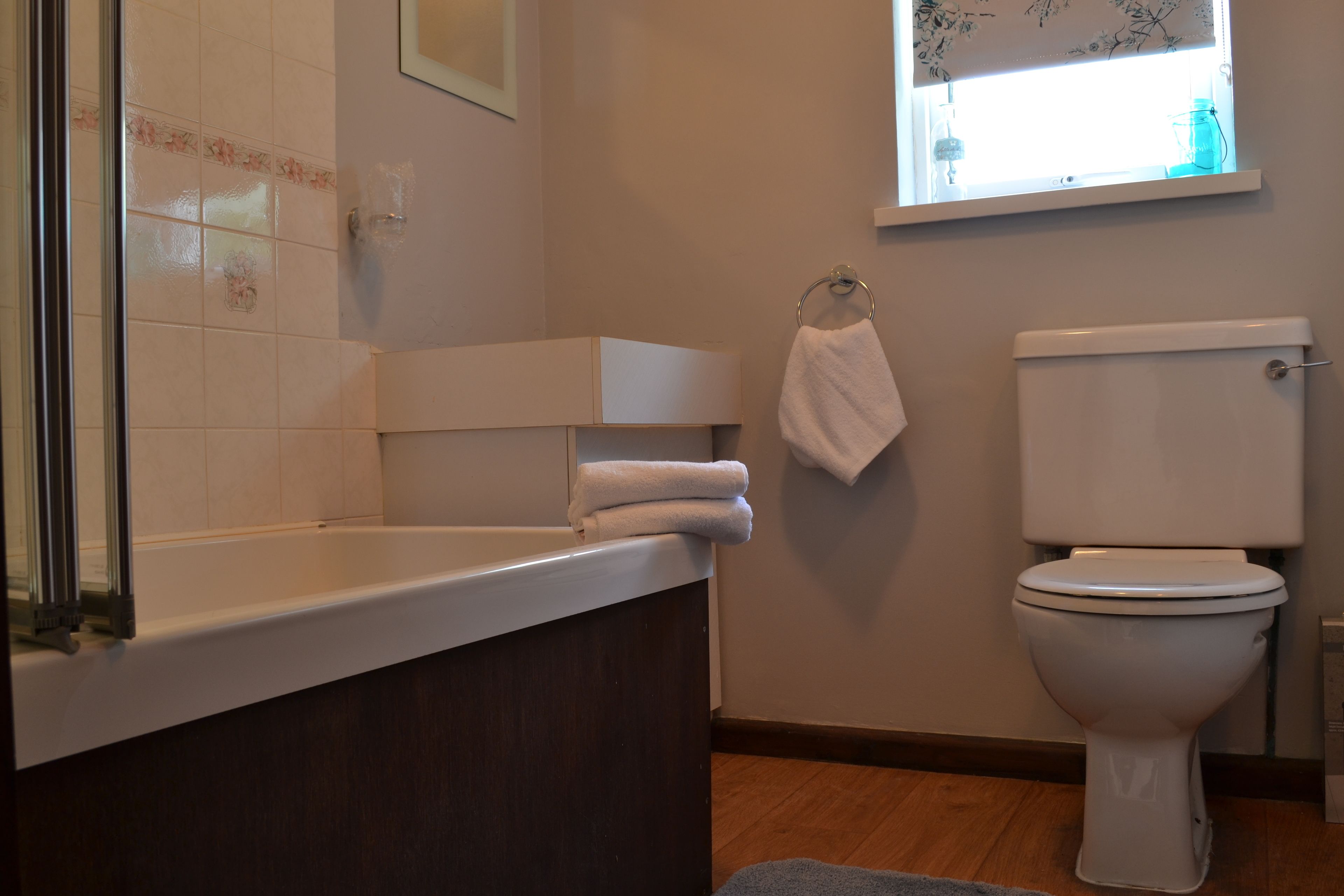 A bathroom with a bathtub, toilet, and a window with a view.