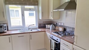 Una cocina compacta con ventana, estufa y lavamanos.