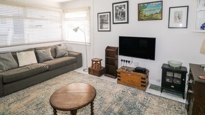 Un salon comprenant un canapé, une table basse en bois, un téléviseur et une cheminée.
