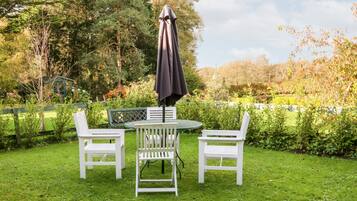 A garden with a table and two chairs, surrounded by a wooden fence and lush greenery.