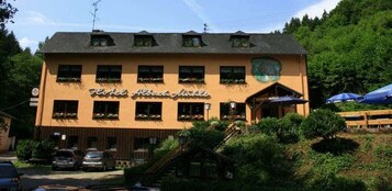 A hotel with a yellow facade, multiple windows, and a sign reading "Hotel Albach Mühle".