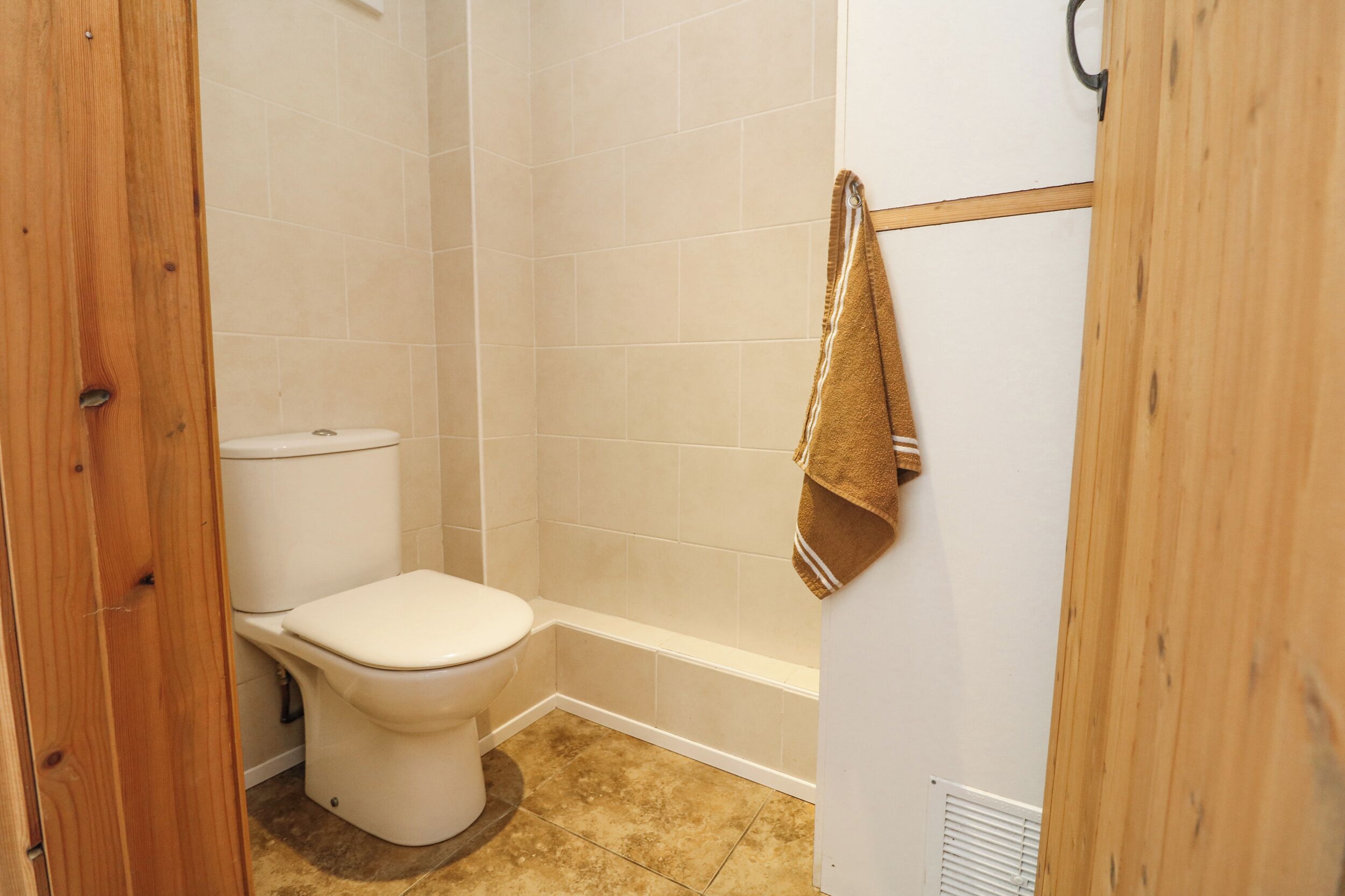 A small, clean bathroom with a toilet, a shower, and a towel rack.